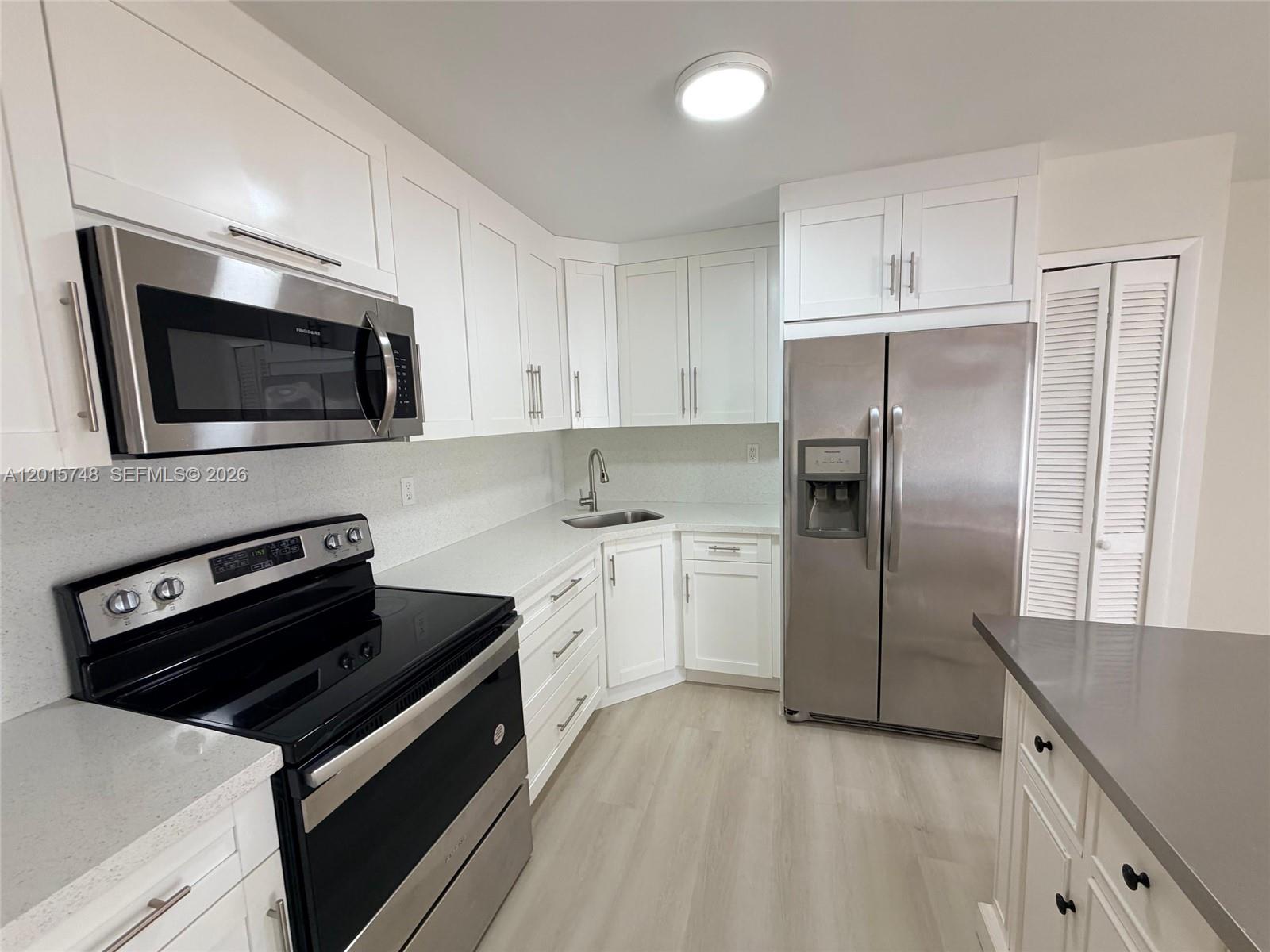 A kitchen features white cabinetry, stainless steel appliances, and light-colored countertops and flooring — 6514 SW 128th Pl # 6514, Miami FL 33183, MIAMI, FL