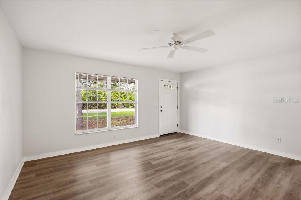 An empty room features light gray walls, wood-look flooring, a ceiling fan, and a window — 2278 PINELLAS DRIVE, PUNTA GORDA, FL