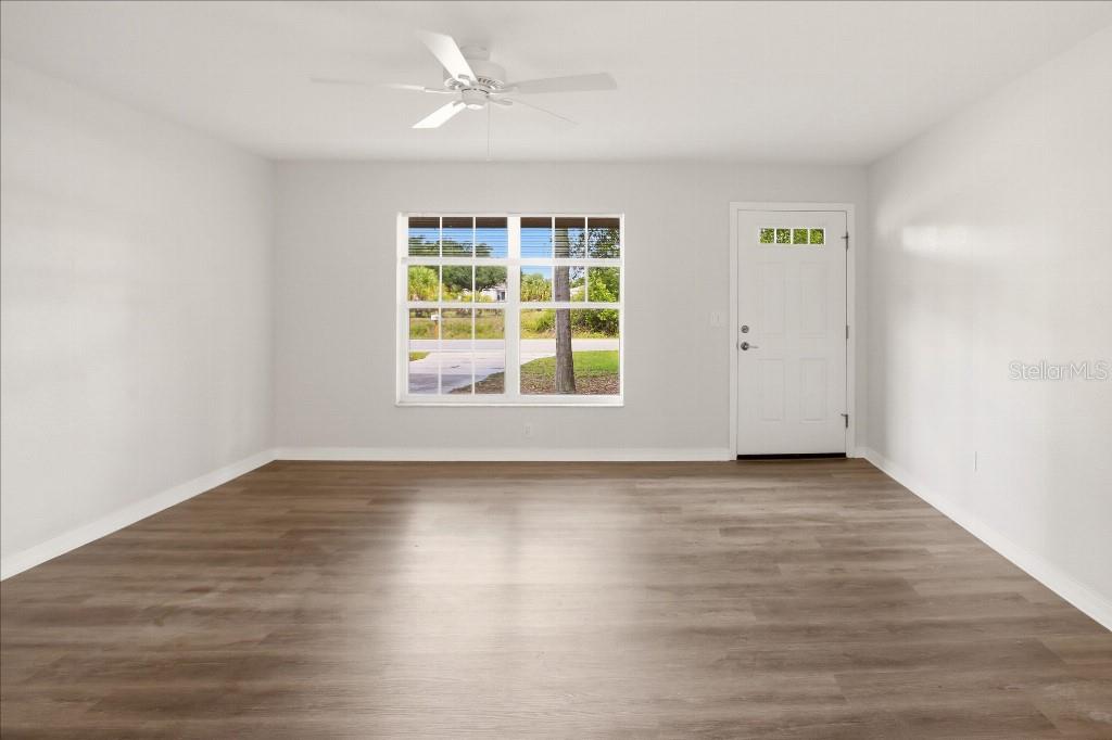 An empty room features light-colored walls, wood-look flooring, a ceiling fan, and a window — 2278 PINELLAS DRIVE, PUNTA GORDA, FL