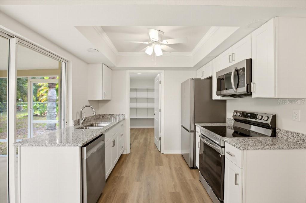 A kitchen with white cabinets, granite countertops, stainless steel appliances, and a walk-in pantry — 2278 PINELLAS DRIVE, PUNTA GORDA, FL