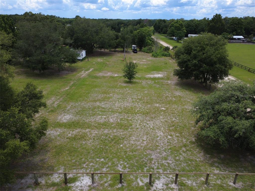 An aerial view of a grassy, partially wooded lot with a fence in the foreground — 38045 COUNTY ROAD 439, EUSTIS, FL