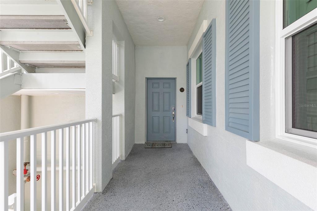 An outdoor entryway features a blue door, light-colored walls, and a gray speckled floor — 800 CINNAMON BEACH WAY UNIT 721, PALM COAST, FL