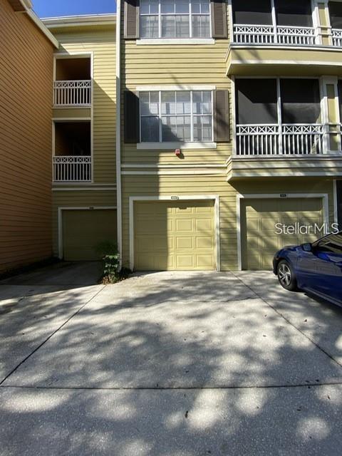 A multi-story tan building features two garage doors and balconies on the upper levels — 5005 CITY STREET UNIT 1317, ORLANDO, FL