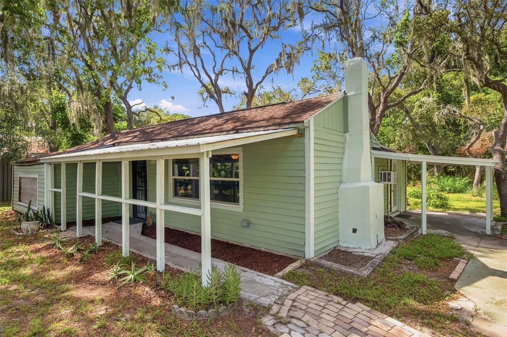 A light green, single-story house with a covered porch and a prominent exterior chimney — 12307 EAGLE LAKE AVENUE, NEW PORT RICHEY, FL