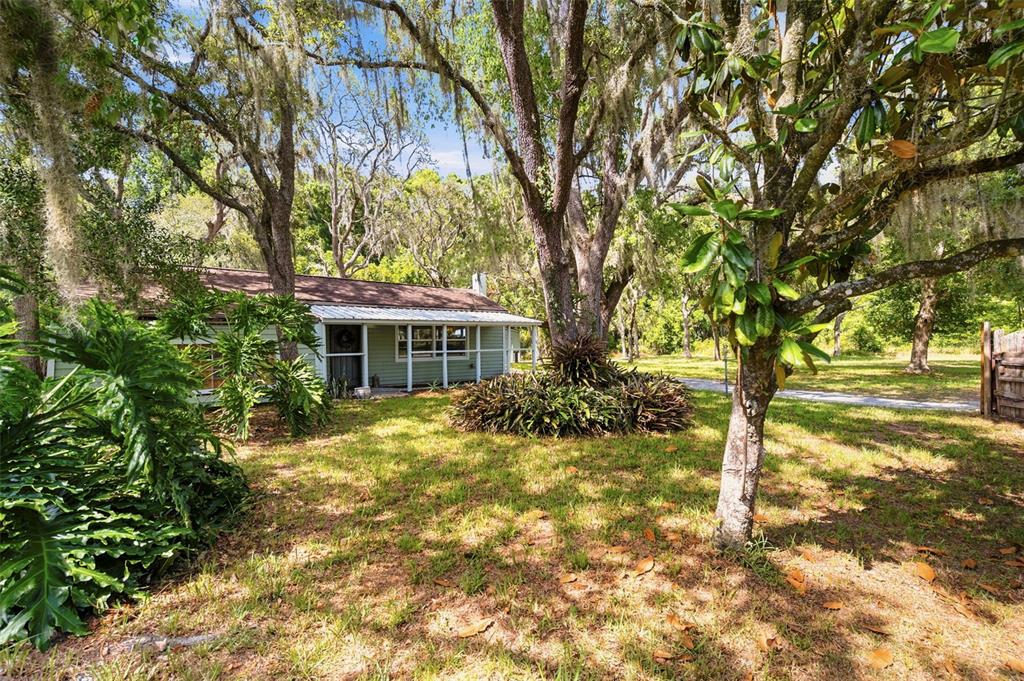 A single-story house with a screened porch sits in a yard shaded by large trees — 12307 EAGLE LAKE AVENUE, NEW PORT RICHEY, FL