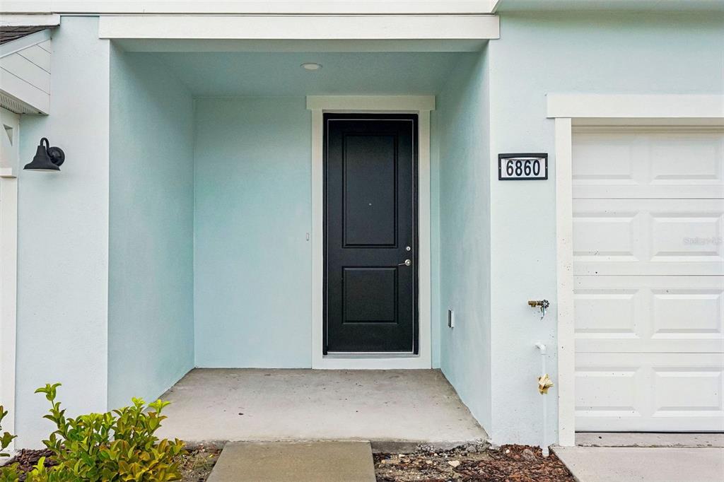 An empty living room features light wood-look flooring, white walls, a staircase, and sliding doors — 6860 HOLCOMBE DOWN DRIVE, ZEPHYRHILLS, FL