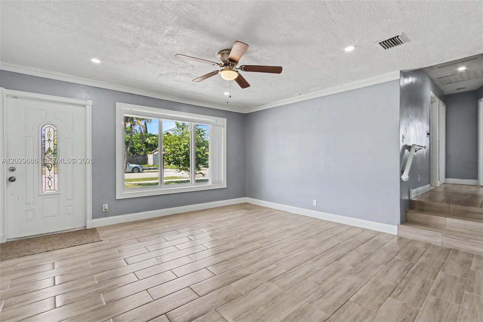 A living room features light gray walls, wood-look tile flooring, a ceiling fan, and stairs — 6230 SW 16th Ct, North Lauderdale FL 33068, NORTH LAUDERDALE, FL