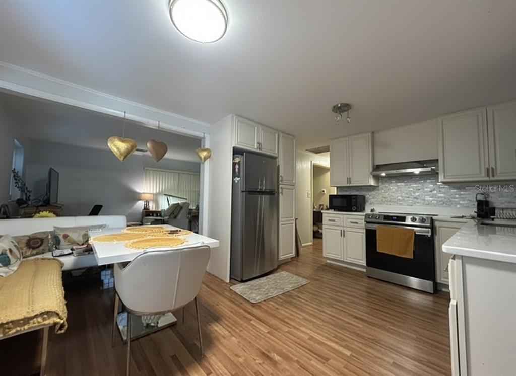 A kitchen with white cabinets, stainless steel appliances, and a dining area with a white table — 2455 ROYAL ROAD, DELAND, FL