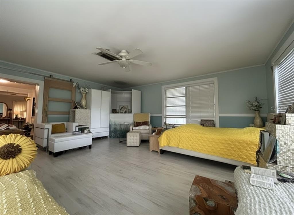 A bedroom features light blue walls, wood-look flooring, a yellow bedspread, and a ceiling fan — 2455 ROYAL ROAD, DELAND, FL