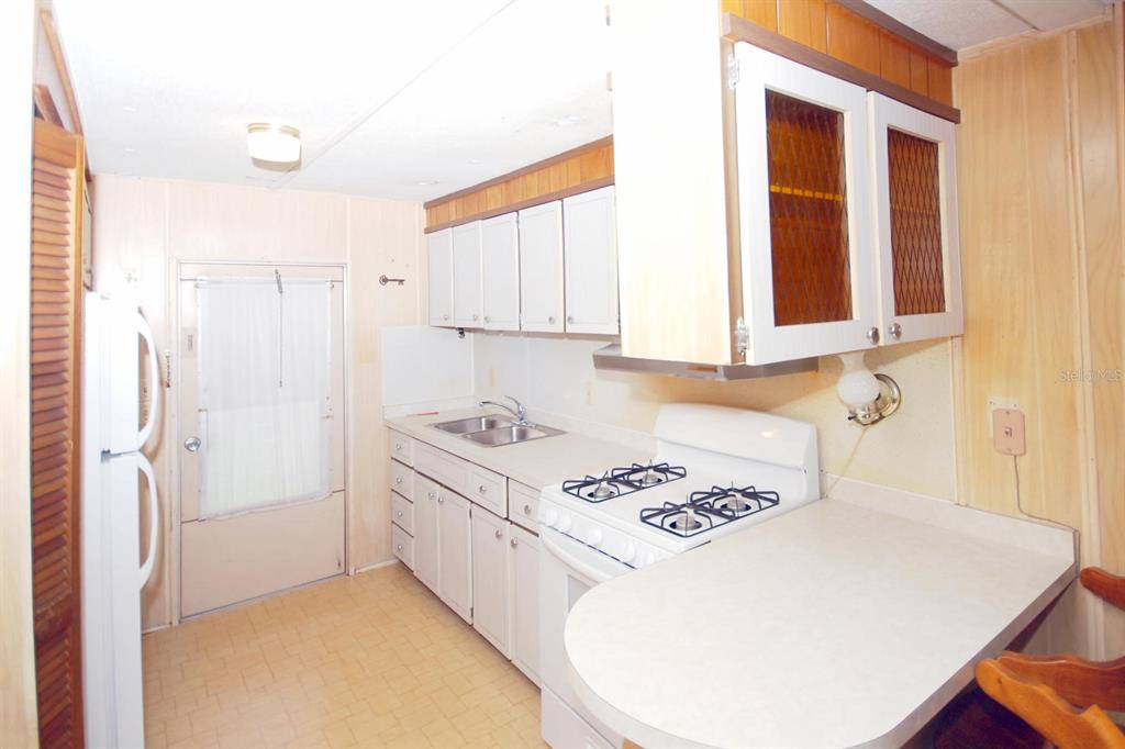 A kitchen features white cabinets, a white stove, a double sink, and light-colored countertops — 8810 COBB ROAD, RIVERVIEW, FL