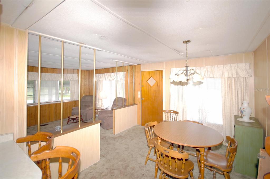 A dining area with a round wooden table and chairs adjacent to a living room — 8810 COBB ROAD, RIVERVIEW, FL