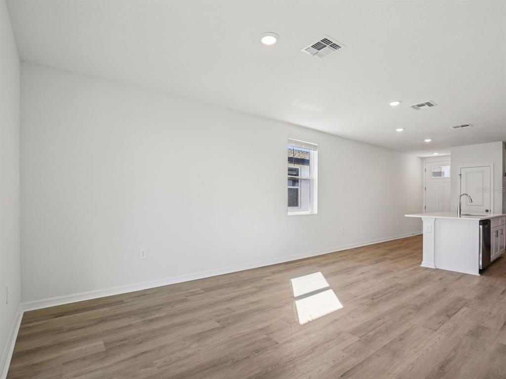 An open-concept living area features white walls, light wood-look flooring, and a kitchen island — 11255 BELLEWOOD TERRACE, PARRISH, FL
