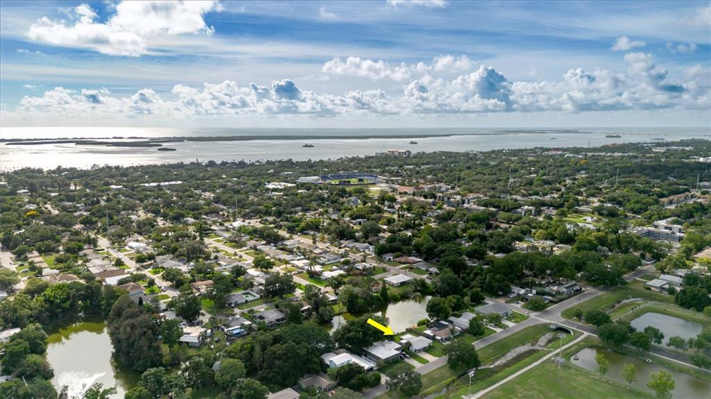 An aerial view shows a residential neighborhood with a house highlighted by a yellow arrow — 96 NEW YORK AVENUE, DUNEDIN, FL
