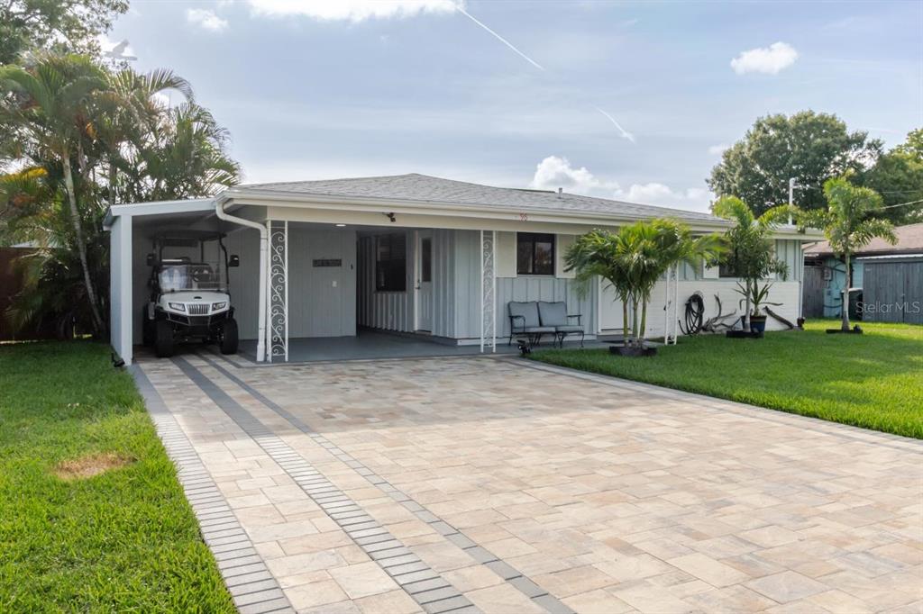 A single-story house with a paved driveway, a carport, and palm trees in the yard — 96 NEW YORK AVENUE, DUNEDIN, FL