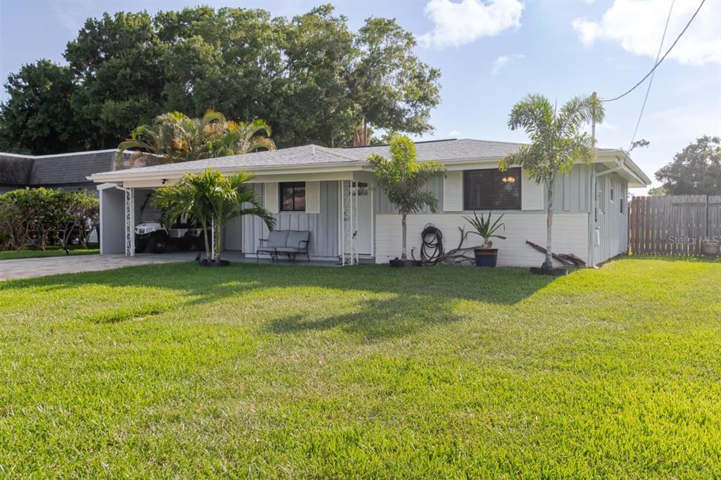 A single-story house with a carport, light-colored siding, and palm trees in the front yard — 96 NEW YORK AVENUE, DUNEDIN, FL