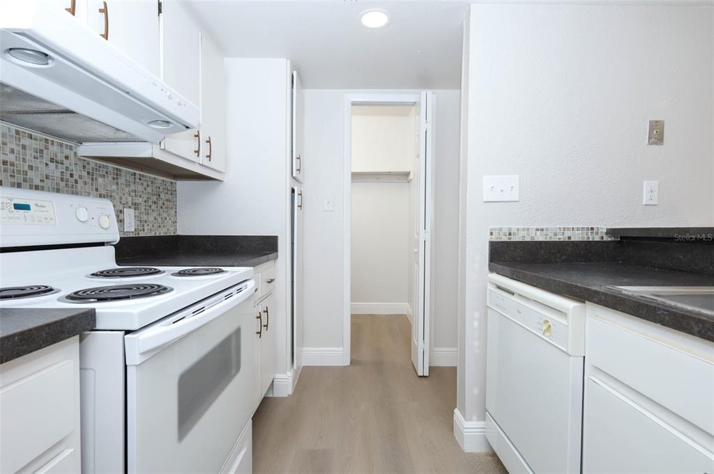 A kitchen features white cabinets, dark countertops, a white stove, and a dishwasher — 4029 HENLEY ROAD UNIT 1705, ORLANDO, FL