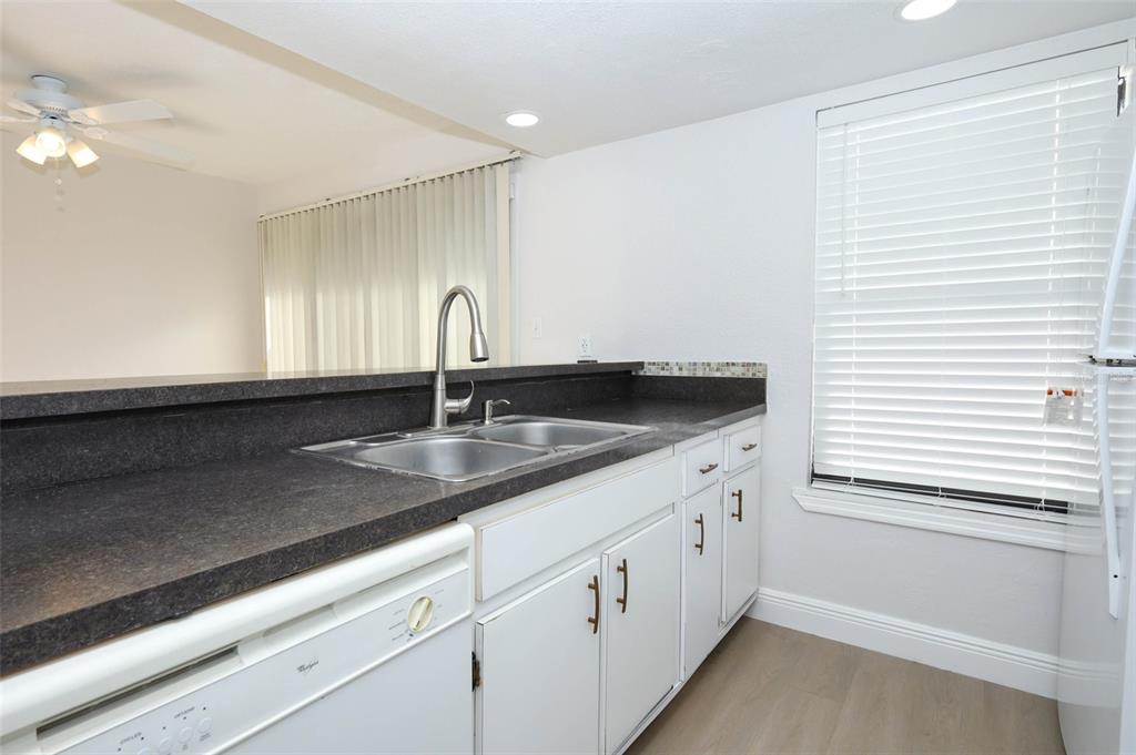 A kitchen features white cabinets, dark countertops, a double sink, and a window with blinds — 4029 HENLEY ROAD UNIT 1705, ORLANDO, FL
