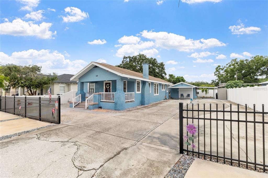 A blue single-story house with a front porch and a detached garage sits behind fences — 710 E BROAD STREET, TAMPA, FL