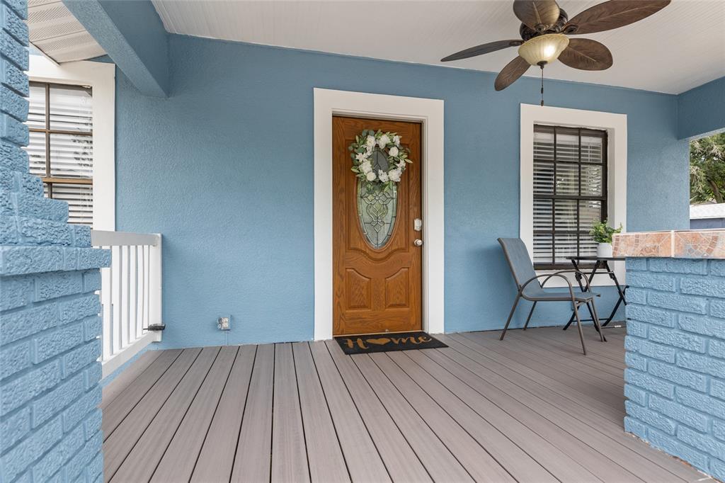 A blue-walled front porch features a wooden door, gray composite decking, and a ceiling fan — 710 E BROAD STREET, TAMPA, FL