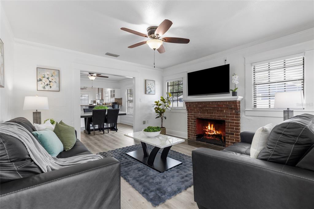 A living room features a brick fireplace, gray leather sofas, and a dining area beyond — 710 E BROAD STREET, TAMPA, FL