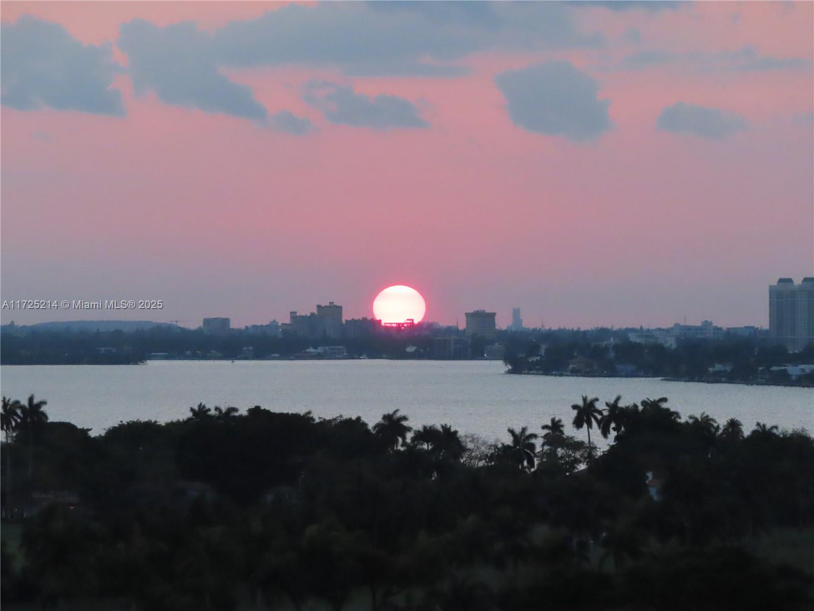 A sunset over a body of water with a city skyline in the distance — 5701 Collins Ave # 1011, Miami Beach FL 33140, MIAMI BEACH, FL