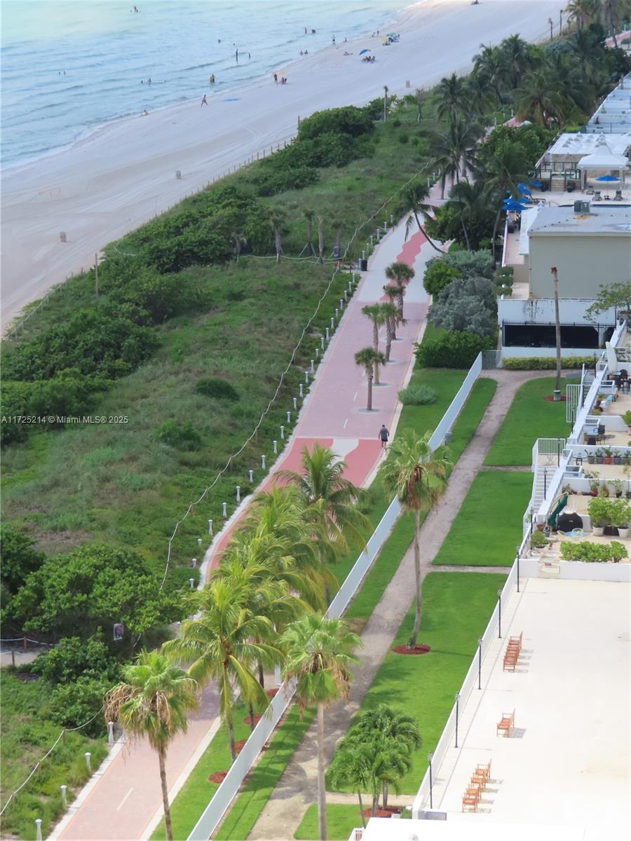 An aerial view shows a red paved walking path, palm trees, and a sandy beach — 5701 Collins Ave # 1011, Miami Beach FL 33140, MIAMI BEACH, FL