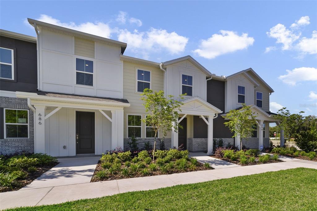 A row of modern two-story townhomes features light-colored siding, brick accents, and covered entryways — 688 LOLA LANE, OVIEDO, FL