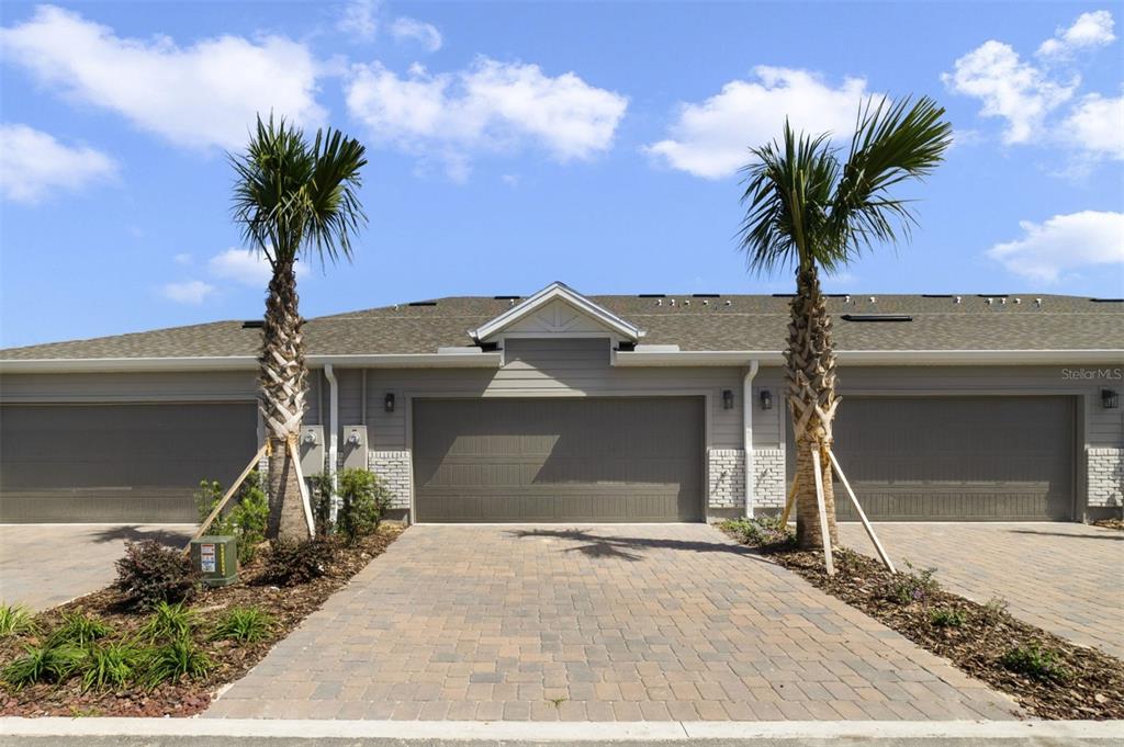 A row of townhome garages with paver driveways and two palm trees in the front — 688 LOLA LANE, OVIEDO, FL