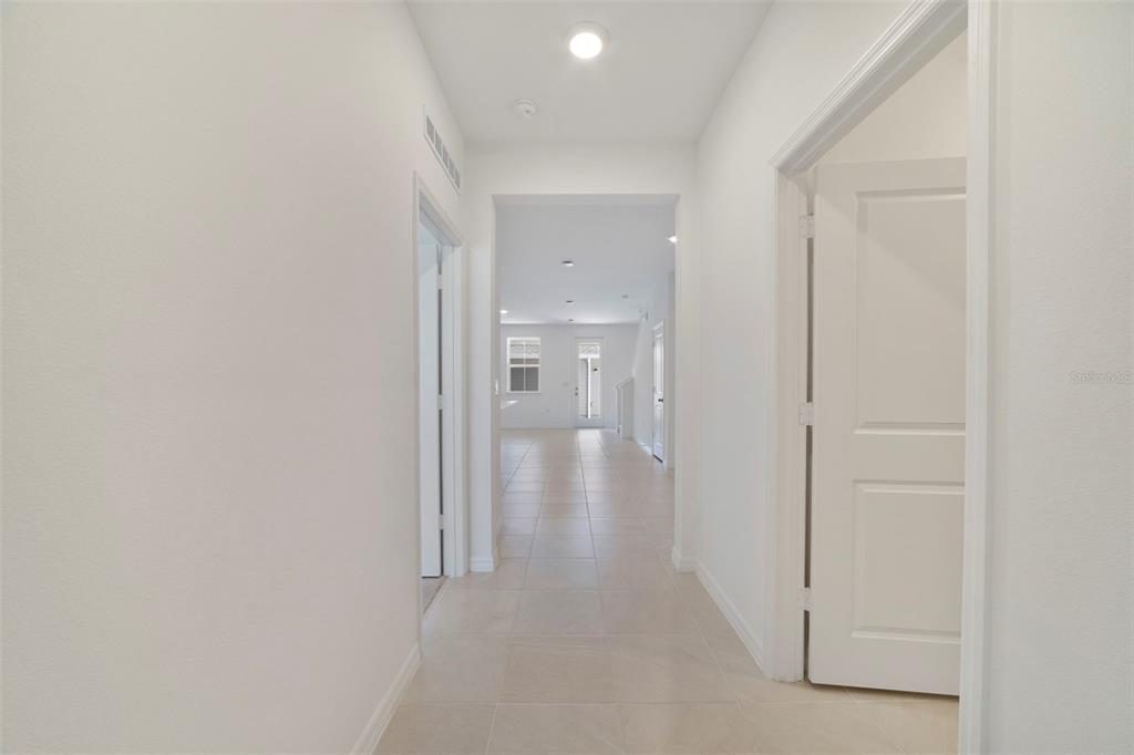 A bright hallway with light-colored tile flooring leads toward an open living area — 688 LOLA LANE, OVIEDO, FL