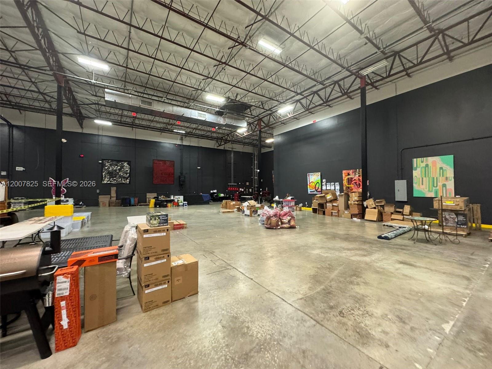 A large, open warehouse space features high ceilings, black walls, and concrete flooring — 3450 NW 115th Ave, Doral FL 33178, DORAL, FL
