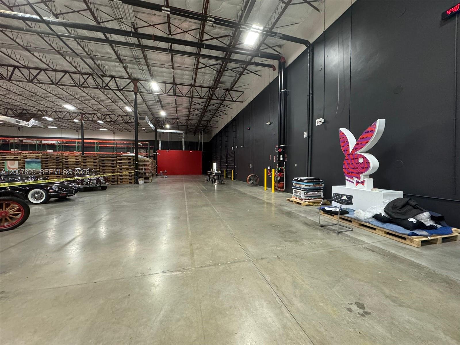 A large industrial warehouse space features a concrete floor, high ceilings, and a Playboy statue — 3450 NW 115th Ave, Doral FL 33178, DORAL, FL