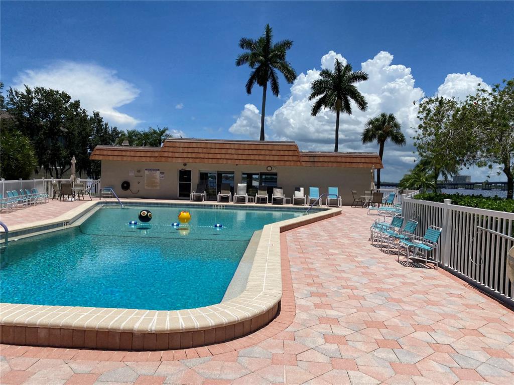 A swimming pool with a paved deck and a clubhouse building under a blue sky — 1600 1ST AVENUE W UNIT 206A, BRADENTON, FL