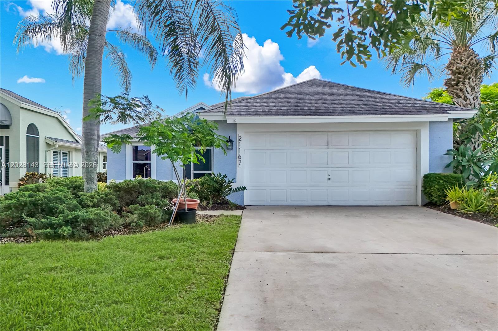A light blue single-story house features a white garage door and a concrete driveway — 21167 Butchers Holler, Estero FL 33928, ESTERO, FL