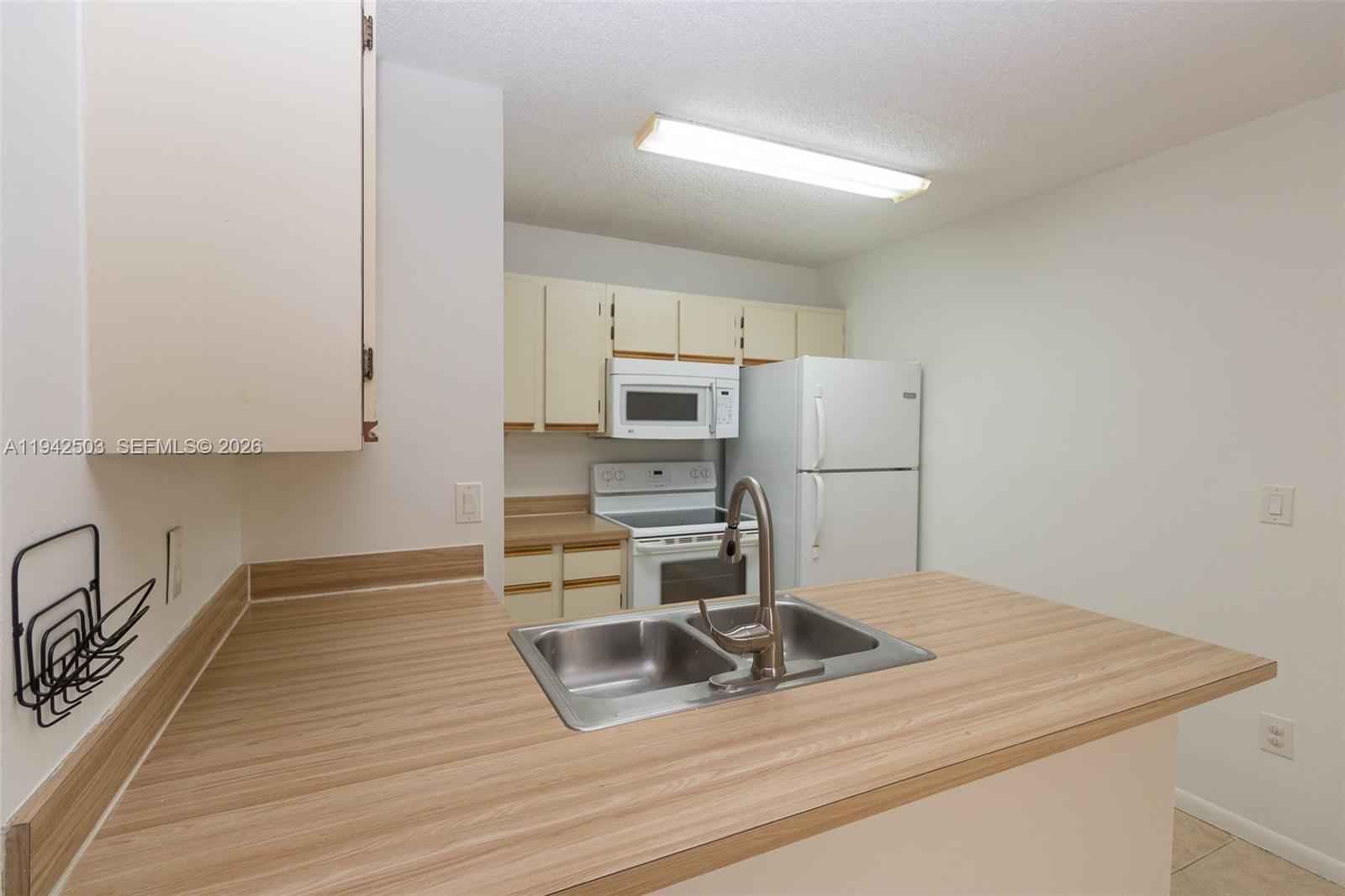 A kitchen features wood-look laminate countertops, white cabinets, and a stainless steel sink — 18328 NW 68th Ave # P, Hialeah FL 33015, HIALEAH, FL