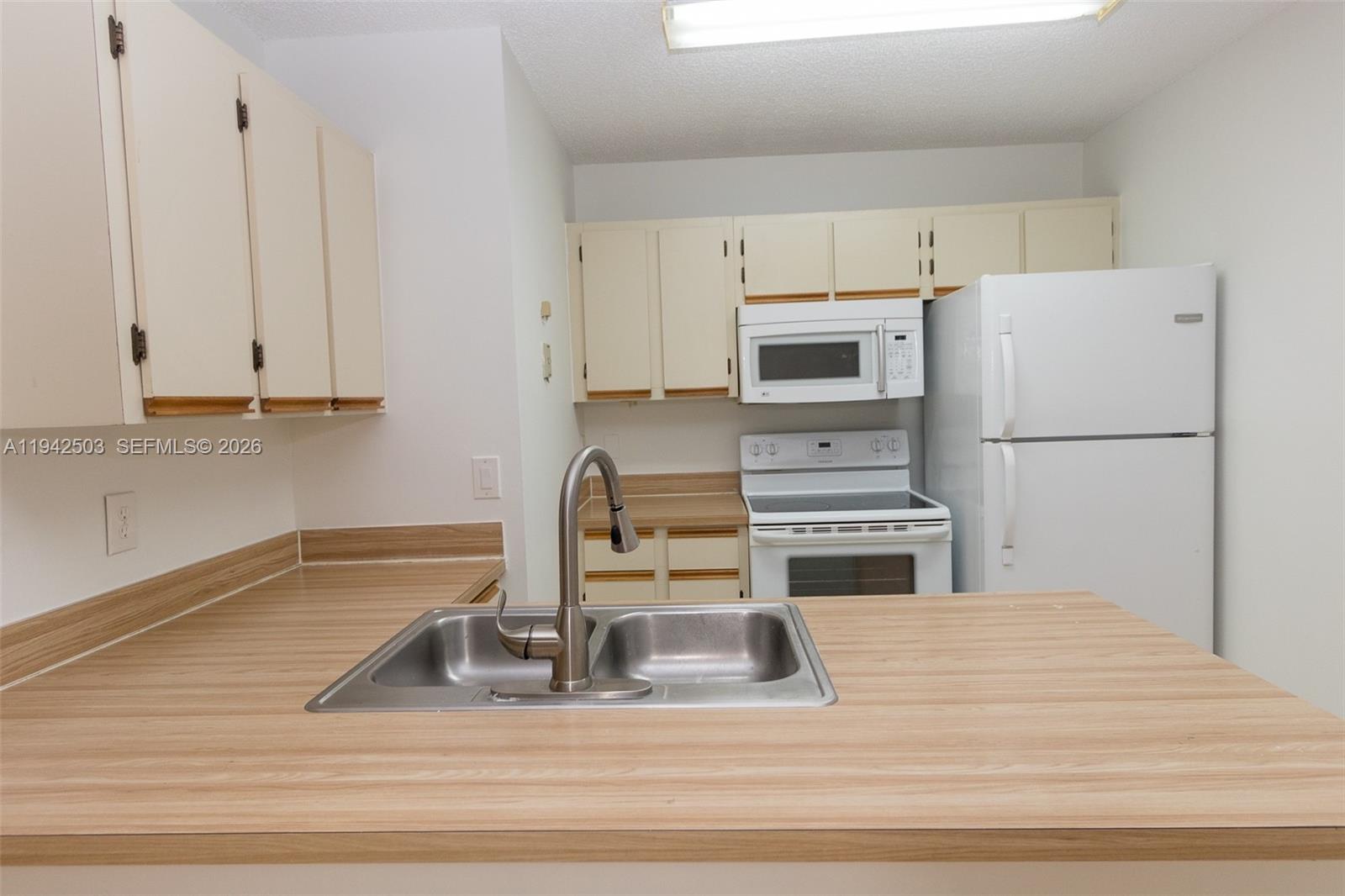 A kitchen features light wood laminate countertops, white cabinets, and a stainless steel sink — 18328 NW 68th Ave # P, Hialeah FL 33015, HIALEAH, FL