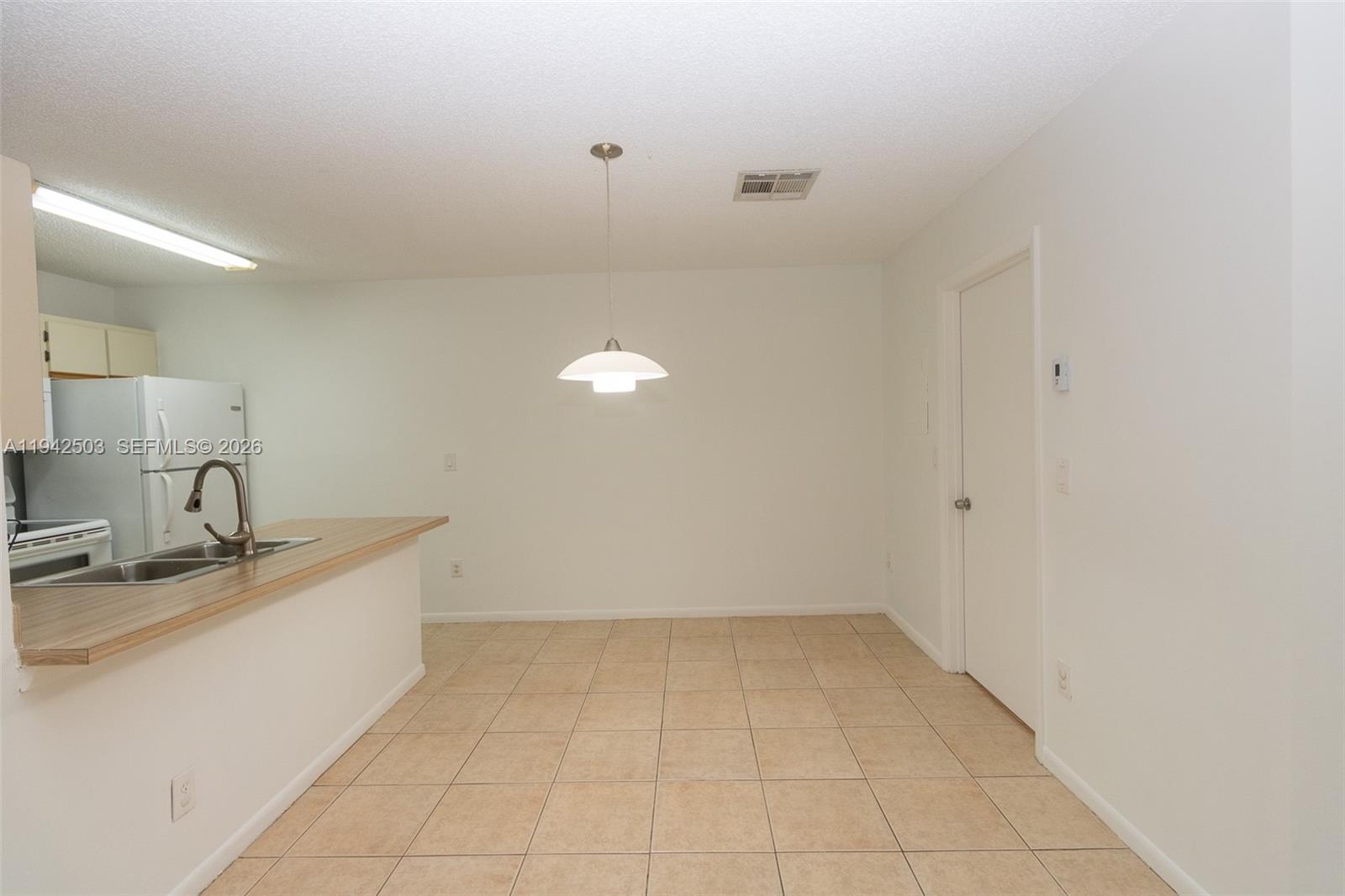 A dining area with tile flooring, a pendant light, and an adjacent kitchen counter — 18328 NW 68th Ave # P, Hialeah FL 33015, HIALEAH, FL