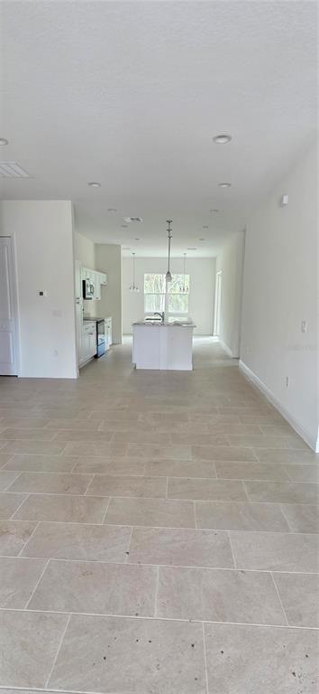 An open-concept kitchen features white cabinetry, a central island, and light-colored tile flooring — 1569 9TH AVENUE, DELAND, FL