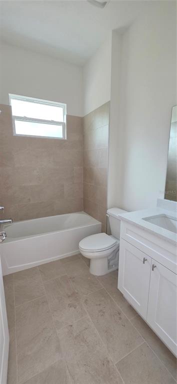 A bathroom features a white vanity, a toilet, and a bathtub with beige tile surround — 1569 9TH AVENUE, DELAND, FL