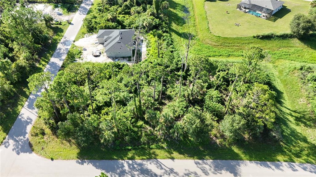 An aerial view shows a wooded residential lot next to a house under construction — N SAN MATEO DRIVE, NORTH PORT, FL