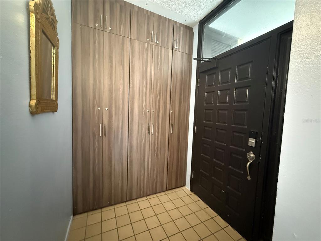 An entryway features wood-look cabinets, a black paneled door, and light-colored square floor tiles — DR BEACH VILLAGE UNIT 119, HUMACAO, PR
