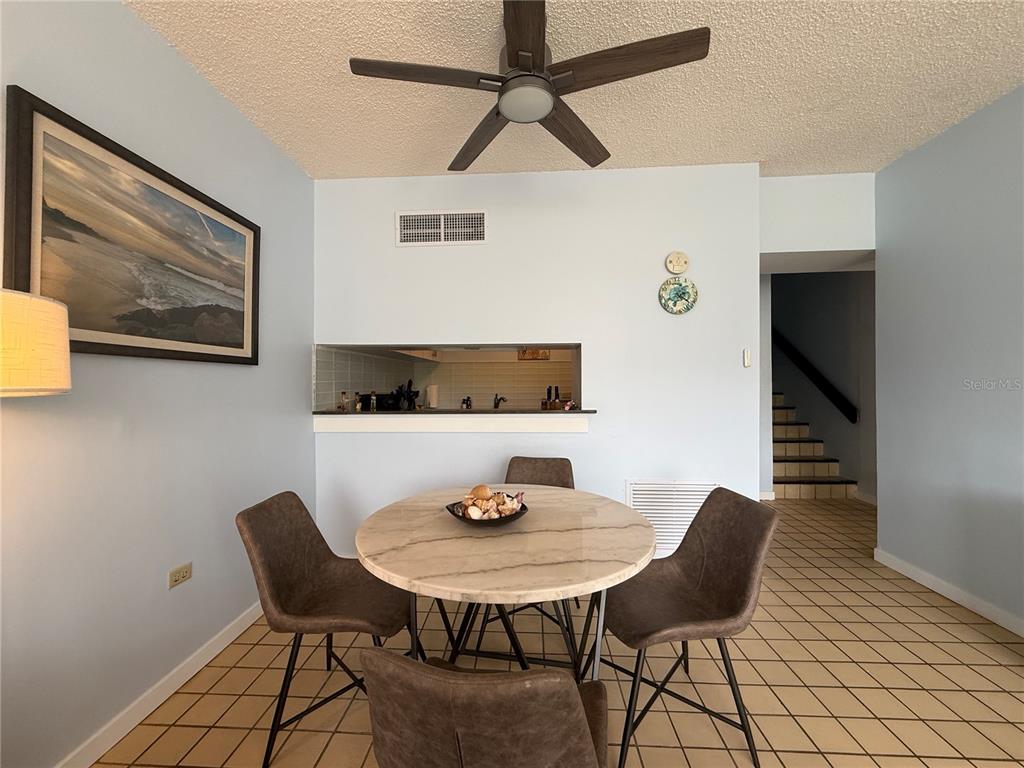 A dining area features a round marble table, four chairs, and a ceiling fan — DR BEACH VILLAGE UNIT 119, HUMACAO, PR