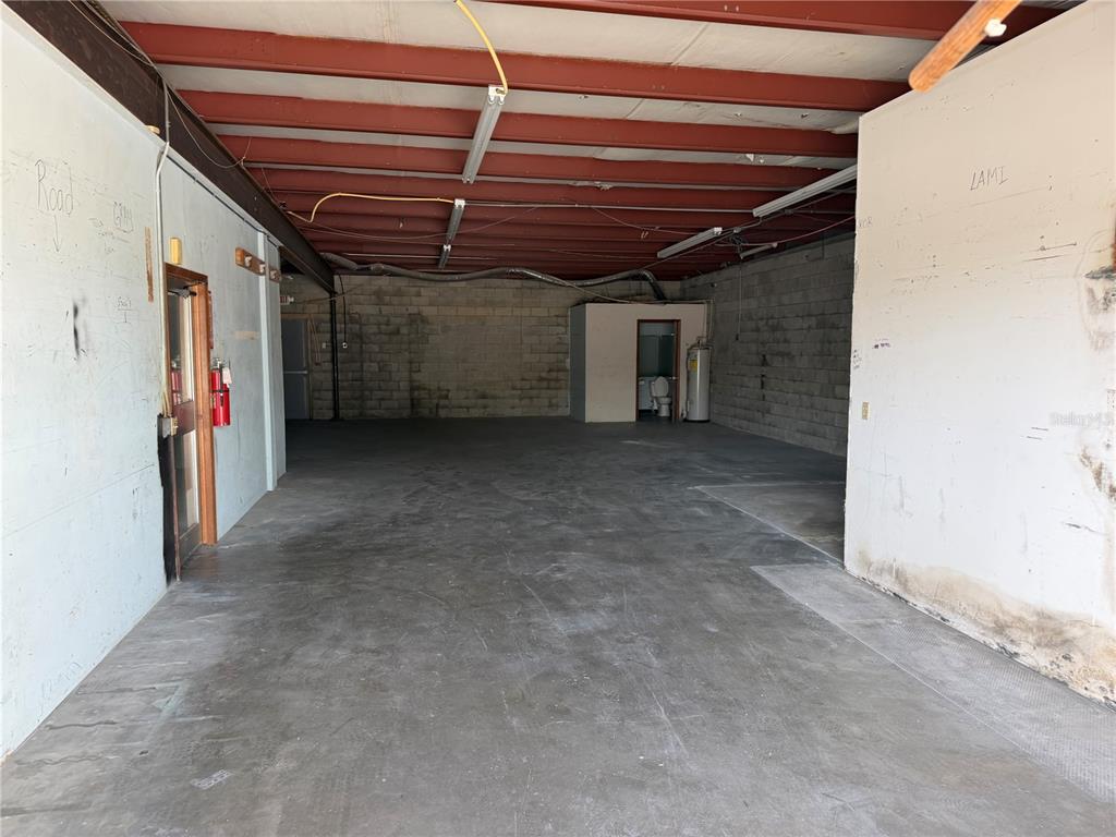 An empty industrial warehouse space features exposed red ceiling beams and concrete block walls — 1706 N MAGNOLIA AVENUE UNIT 101, OCALA, FL