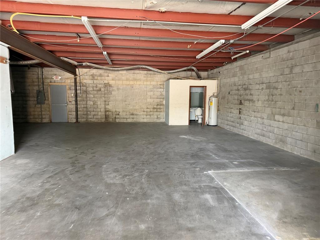 An industrial warehouse space features concrete block walls, a concrete floor, and exposed ceiling beams — 1706 N MAGNOLIA AVENUE UNIT 101, OCALA, FL