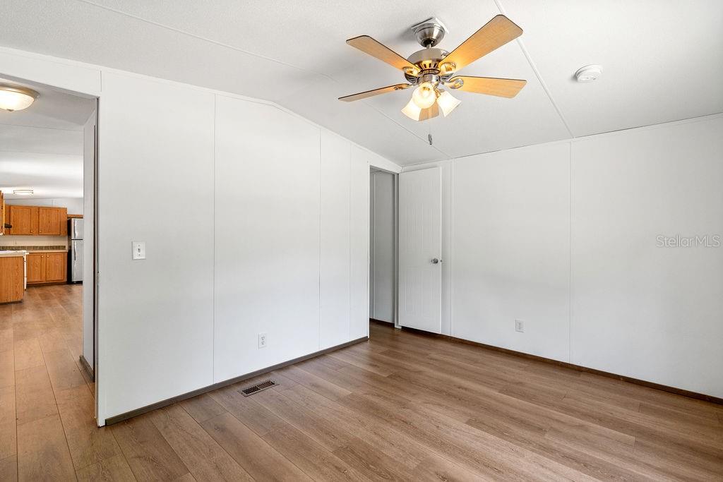 An interior view of a room with white walls, wood-look flooring, and a ceiling fan — 27133 MILLER ROAD, DADE CITY, FL