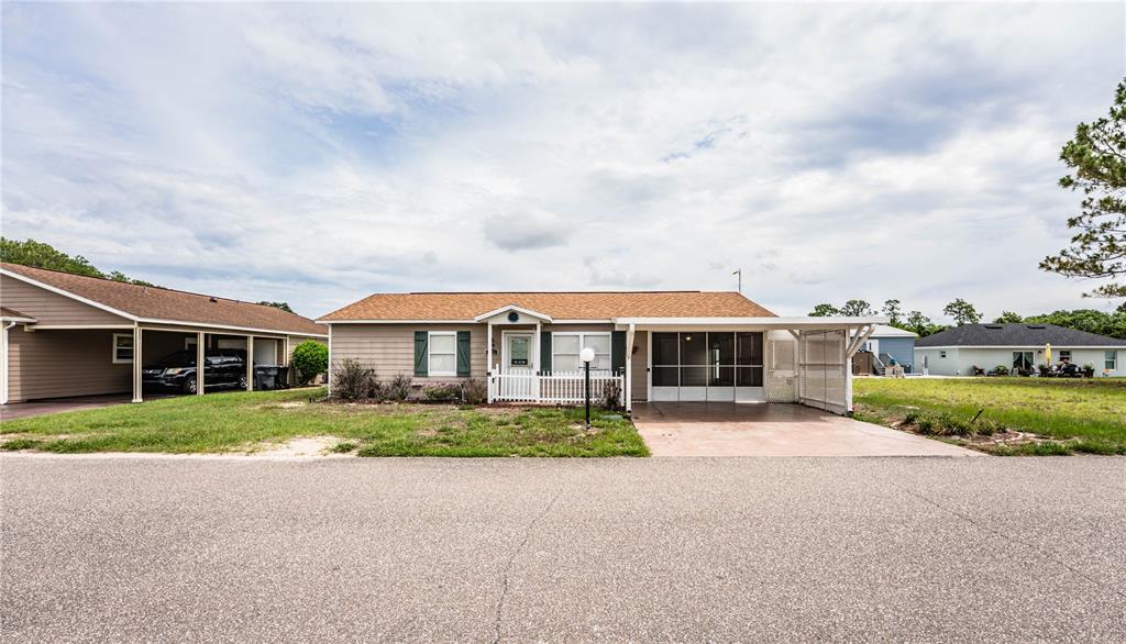 A single-story house with a tan exterior, brown roof, and an attached screened-in carport — 4235 CERIMEN STREET, LAKE WALES, FL