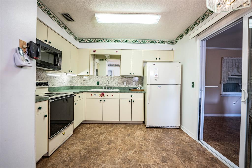A kitchen with cream cabinets, green countertops, white appliances, and a vinyl floor — 4235 CERIMEN STREET, LAKE WALES, FL