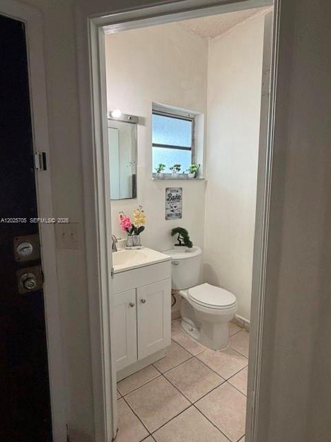 A small bathroom features a white vanity, a toilet, and a window with tiled flooring — 4424 W 12th Ln # 7, Hialeah FL 33012, HIALEAH, FL