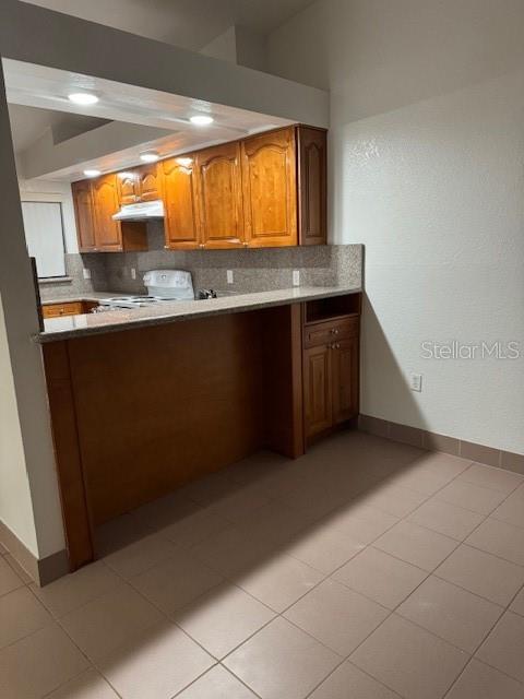 A kitchen features wood cabinets, a breakfast bar, and light-colored tile flooring — 25385 SANDHILL BOULEVARD UNIT D2, PUNTA GORDA, FL