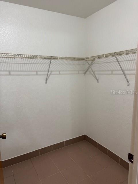 A walk-in closet features white walls, tile flooring, and wire shelving along the walls — 25385 SANDHILL BOULEVARD UNIT D2, PUNTA GORDA, FL