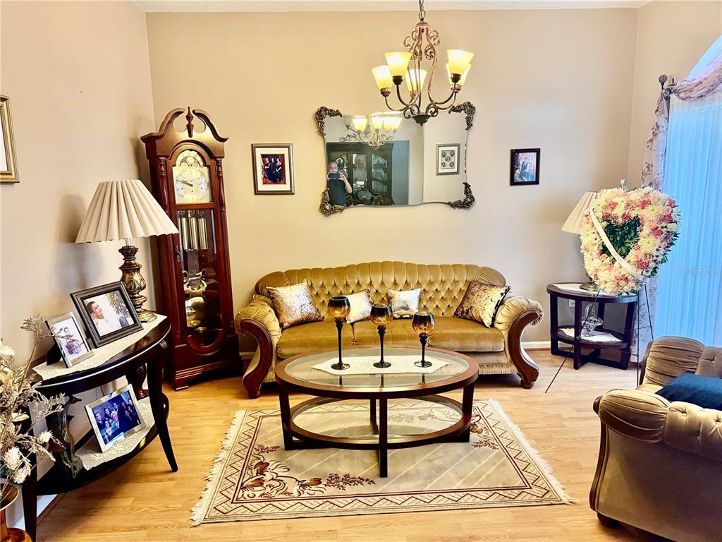 A living room features a tufted gold sofa, a grandfather clock, and a glass coffee table — 68 RIVERVIEW DRIVE, PALM COAST, FL